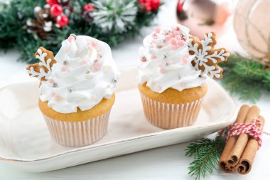 Noel dekorlu lezzetli kekler ve beyaz ahşap masa üzerinde tarçın, yakın plan.