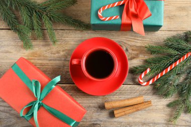Fincanda romatik kahve, hediye kutuları ve tahta masanın üzerinde köknar ağacı dalları. Noel tebrik kartı.