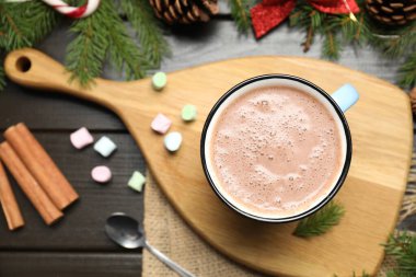 Bardakta sıcak kakao, marşmelov ve koyu ahşap masada Noel süsü.