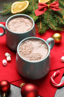 Lezzetli sıcak kakao, marşmelov ve Noel dekoru ahşap masada, yakın plan.