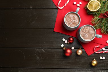 Lezzetli sıcak kakao, marşmelov ve siyah ahşap masada Noel süsü, düz uzanmış