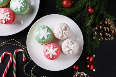 Lezzetli badem kurabiyeleri ve Noel süsleri siyah masada, düz yerde.