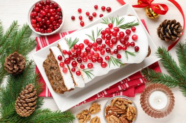 Beyaz ahşap masada kremalı, yaban mersinli, biberiyeli ve şenlikli bir Noel pastası.