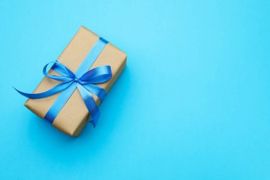 Açık mavi arka planda kurdeleli bir hediye kutusu, üst manzara. Metin için boşluk