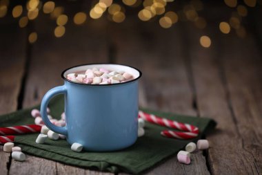 Ahşap masada lokum ve şeker kamışlı lezzetli kakao bulanık Noel ışıklarına karşı, yakın plan. Metin için boşluk