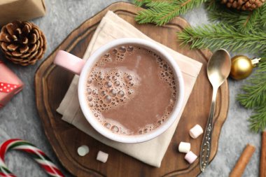 Lezzetli kakao, marşmelov, tarçın, şeker kamışı ve Noel süsü gri masada, düz uzanmış