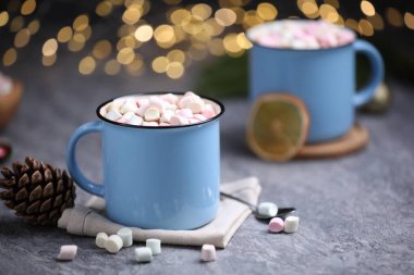 Gri masasında lokum bulunan lezzetli kakao bulanık Noel ışıklarına karşı, yakın plan.