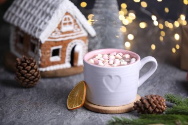 Gri masada lokum ve Noel dekoru olan lezzetli kakao bulanık ışıklara karşı, yakın plan.