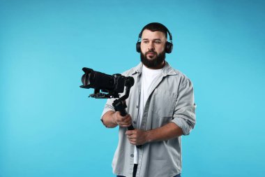 Kameraman açık mavi arkaplanda kameralı titreşimli dengeleyici kullanıyor. Metin için boşluk