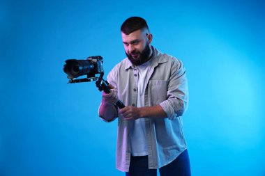 Açık mavi arkaplanda kameralı titreşim dengeleyici kullanan kameraman