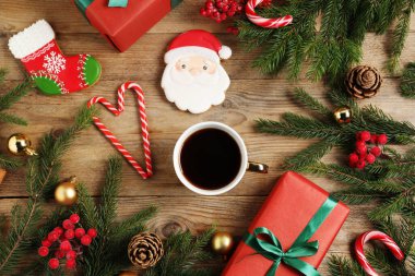 Fincanda romatik kahve, zencefilli kurabiye, hediye kutuları ve ahşap masada Noel süsü, düz uzanma.