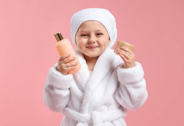 Pembe arka planda kozmetik ürünleri olan bornozlu hoş bir kız.