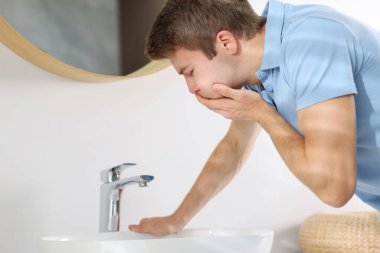 Genç adam lavaboda mide bulantısı çekiyor.