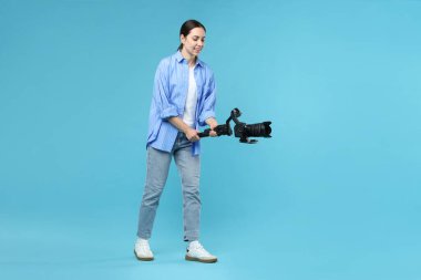 Açık mavi arkaplanda kameralı titreşim dengeleyici kullanan kameraman