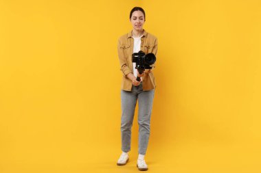 Sarı zemin üzerinde kamera olan titreşimli dengeleyici kullanan kameraman