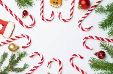 Lezzetli baston şekerlerden ve beyaz arka planda Noel dekorundan yapılmış bir çerçeve. Metin için boşluk