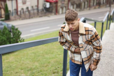 Genç adam mide ağrısı ve açık havada mide bulantısı çekiyor. Metin için boşluk