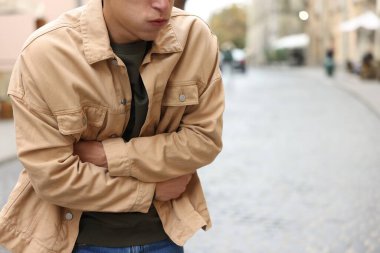 Genç adam mide ağrısı ve mide bulantısı çekiyor. Yakın plan. Metin için boşluk