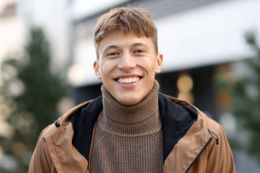 Şehirde ceketli gülümseyen bir adamın portresi.