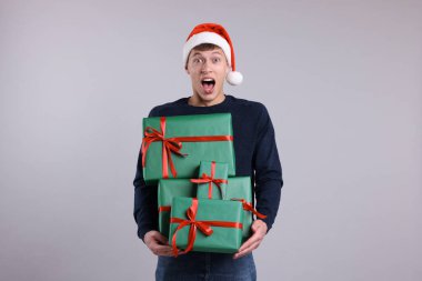 Noel Baba şapkalı duygusal bir adam. Gri arka planda bir sürü hediye kutusu var. Noel ve Yeni Yıl Kutlaması