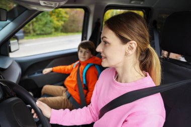 Anne oğlunu arabayla okula götürüyor.