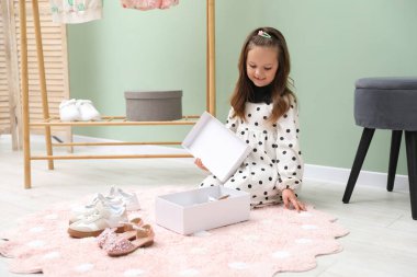 Küçük kız dükkanda farklı ayakkabılar seçiyor.