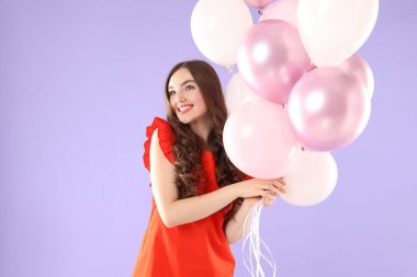 Menekşe arka planda balonları olan güzel bir kadın.