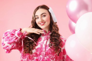 Pembe arka planda balonları olan güzel bir kadın.