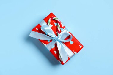 Açık mavi arka planda şeker kamışı ile süslenmiş Noel hediyesi.