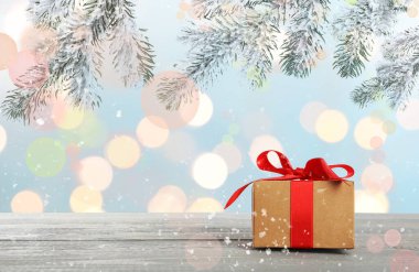 Mutlu Noeller ve Mutlu Noeller kartı. Köknar ağacı dallarının altındaki hediye kutusunda Bokeh ışıkları arka planında bulanıklaştırılmış