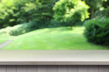 Dışarıdaki boş tahta masa. Arka planda bulanık bahçe. Tasarım için boşluk