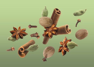 Noel içecekleri için farklı baharatlar ve yeşil arkaplana düşen yemekler. Anason, kakule, tarçın, hindistan cevizi ve karanfil.