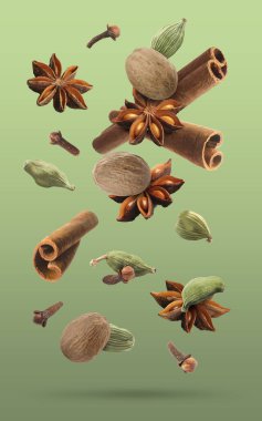 Noel içecekleri için farklı baharatlar ve yeşil arkaplana düşen yemekler. Anason, kakule, tarçın, hindistan cevizi ve karanfil.