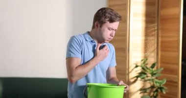 İçeride mide bulantısı çeken kovalı genç bir adam. Kamera izleme