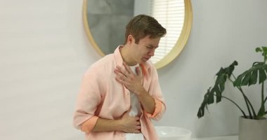 Banyoda mide bulantısı ve mide ağrısı çeken genç bir adam. Kamera hareket ediyor