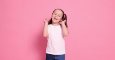 Pembe arka planda poz veren şirin küçük kız.