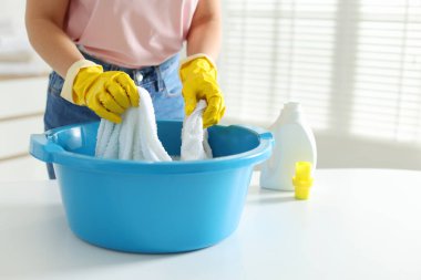 Beyaz masadaki plastik leğende havluları yıkayan kadın, yakın plan. Metin için boşluk