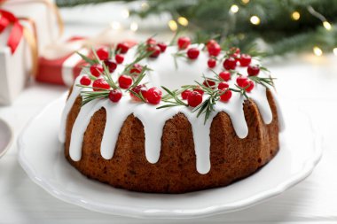 Beyaz masada kremalı, kızılcıklı ve biberiyeli lezzetli bir Noel pastası.