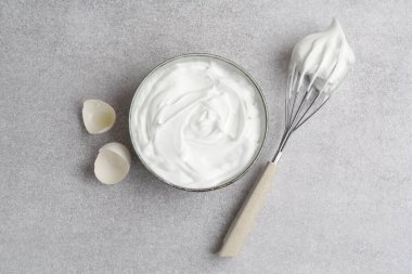 Yumurta beyazlarını kasede çırpmak, yumurta kabuğu ve çırpmak gri desenli masa, düz uzanmak