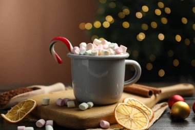 Lezzetli sıcak kakao, şekerleme kamışı ve kurutulmuş portakal dilimleri ahşap masada bulanık Noel ışıklarına karşı, yakın çekim