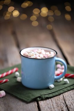 Ahşap masada lokum ve şeker kamışlı lezzetli kakao bulanık Noel ışıklarına karşı, yakın plan. Metin için boşluk