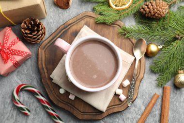 Lezzetli kakao, marşmelov, tarçın, şeker kamışı ve Noel süsü gri masada, düz uzanmış