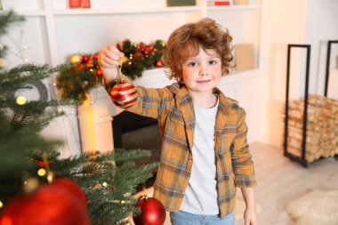 Evde Noel ağacı süsleyen küçük çocuk.