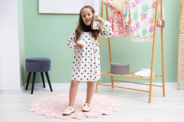 Küçük kız dükkanda farklı ayakkabılar deniyor.