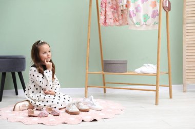 Küçük kız dükkanda farklı ayakkabılar seçiyor.