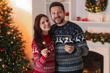 Havai fişekli mutlu çift Noel için dekore edilmiş odada birlikte vakit geçiriyor.