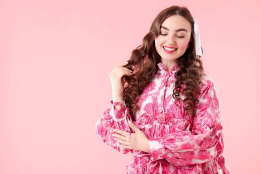 Pembe arka planda güzel giyimli genç bir kadın, mesaj için yer var.