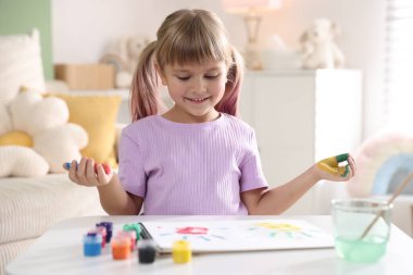 Beyaz masalarda avuç içleri çizen sevimli küçük kız.