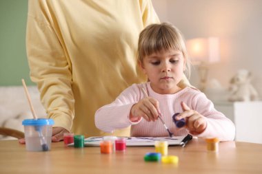 Anne ve küçük kızı ahşap masada birlikte resim çiziyorlar, yakın plan.