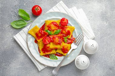 Gri masada servis edilen domates soslu ve fesleğenli lezzetli ravioli.